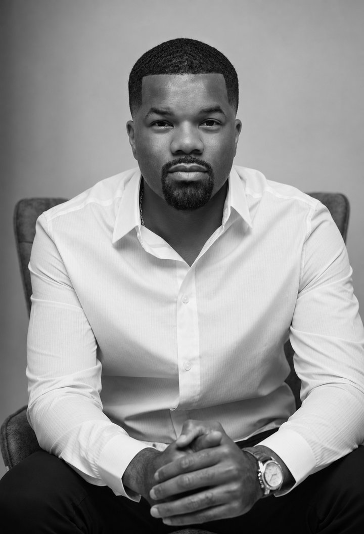 Chris Marvel Davis in a white shirt, seated, hands folded, black and white portrait.